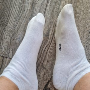 Getragene Socken stark riechend in Crocs und Turnschuh